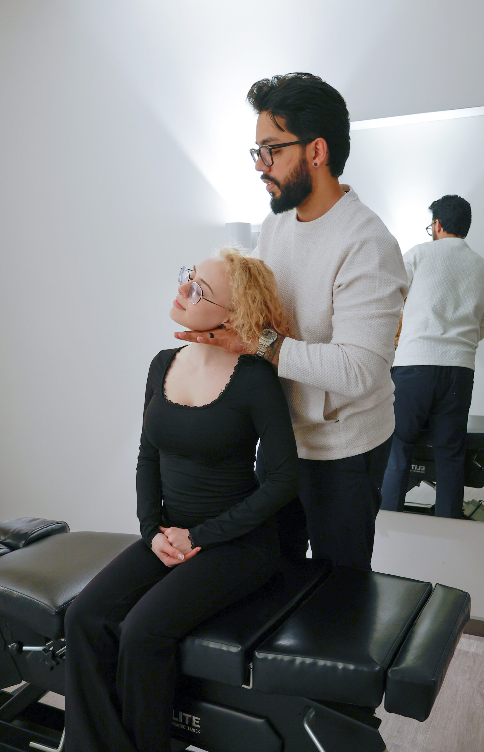 Chiropractor performing a neck adjustment on a seated patient, assisting with neck pain relief in a professional clinic setting.